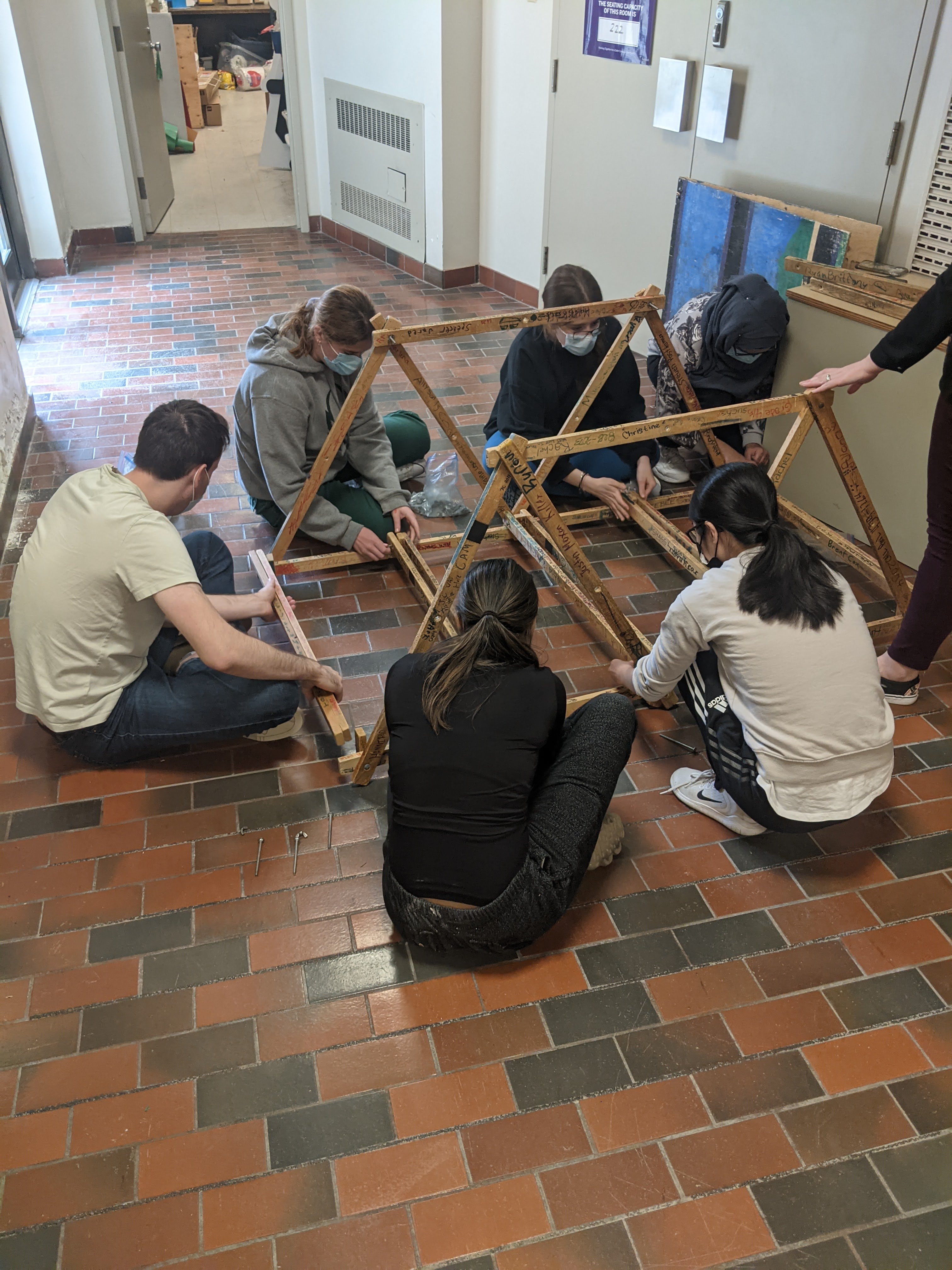 Samantha supports student staff in building a truss bridge for STEM outreach.